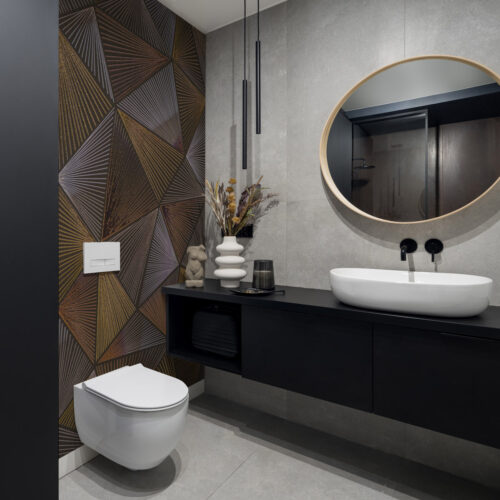 Toilet met geometrisch naadloos fotobehang, ronde spiegel en zwart badkamermeubel in moderne stijl.